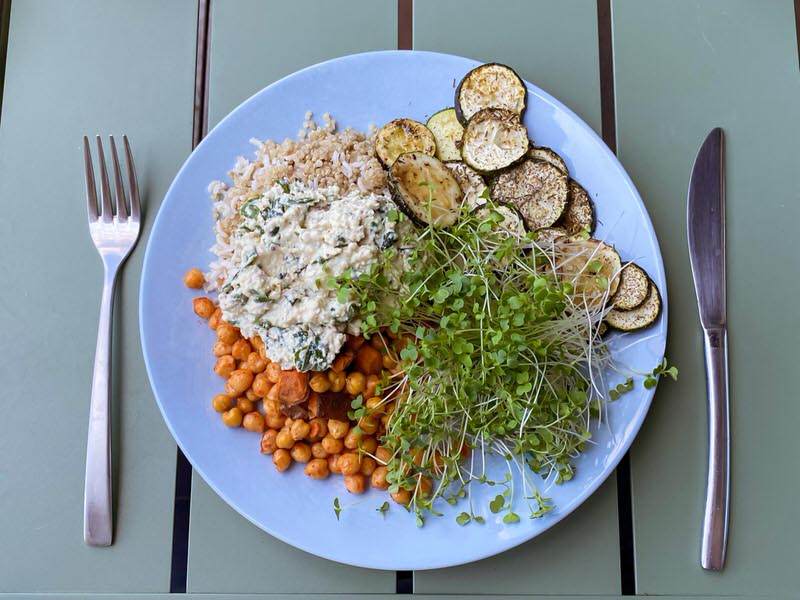Plate with broccoli microgreens, chickpeas, mustard dressing, quinoa and zucchini
